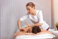 Side view professional masseuse performing with hands back massage to young woman client in wellness spa center. Beauty photo and