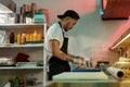 Side view of professional sushi chef looking focused while adding ingredients, spreading them over nori sheet, making Royalty Free Stock Photo