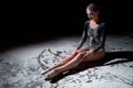 side view of professional tired young female ballet dancer in bodysuit sitting on floor Royalty Free Stock Photo