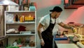 Side view of professional young sushi chef adding ingredients over nori sheet while making delicious rolls at commercial Royalty Free Stock Photo