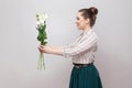 Side view profile of attractive romantic young woman in striped shirt and green skirt holding bouquet of white flowers and giving Royalty Free Stock Photo