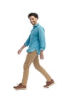 side view of proud casual man with curly hair smiling and walking Royalty Free Stock Photo