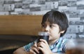 Side view Prtrait of Cute kid sitting on table drinking cold drink in restaurant, Toodler drinking soda or soft drink with straw, Royalty Free Stock Photo