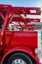 Side view of red big rig car hauler semi trucks with semi trailers standing in row on the parking lot at sunshine Royalty Free Stock Photo