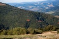 Side view of red chairlift ride to mountains with beautiful nature background.