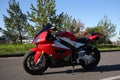 Side view of the red sport motorcycle standing alone on the parking. Blue sky, green trees and grass on the background Royalty Free Stock Photo