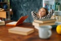 Side view of relaxed happy pupil school girl kid sitting with paper book and notebook at desk, leaning back on chair Royalty Free Stock Photo