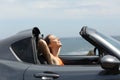 Relaxed tourist in a roadster car on summer vacations