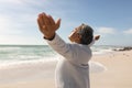 Side view of retired senior biracial man standing with arms outstretched at beach on sunny day Royalty Free Stock Photo