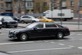 Side view rolling shot with black car in motion. Mercedes-Benz Maybach S560 driving along the street in city with blurred