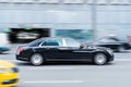 Side view rolling shot with black car in motion. Mercedes-Benz Maybach S560 driving along the street in city with blurred