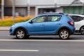 Side view rolling shot with Dacia Sandero Stepway subcompact car second generation B52. Fast moving blue small hatchback with