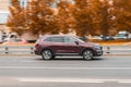 side view rolling shot with Renault Koleos Second generation (HC) in Maroon color in motion. SUV driving fast