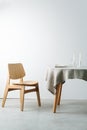 Side view of a round table with a white tablecloth and a chunky wooden chair Royalty Free Stock Photo