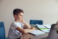 Side view on sad Caucasian boy pupil doing homework and being lazy. Learning at home. Royalty Free Stock Photo