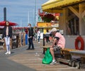 Side view of a sad poor man sitting on the wooden bench on a sunny day in Fisherman Wharf Victoria Royalty Free Stock Photo