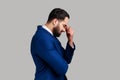 Side view of sad unhappy bearded businessman hiding face in hand crying, feeling stressed worried. Royalty Free Stock Photo