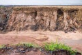 Side view of the sandstone soil layer under the asphalt road, which was eroded by rain and wild water flows Royalty Free Stock Photo