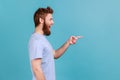 Side view of satisfied bearded man pointing aside, showing blank copy space for idea presentation. Royalty Free Stock Photo