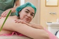 Side view of satisfied smiling female patient receiving back massage. Looks into the camera. Blurry Royalty Free Stock Photo