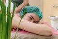 Side view of satisfied smiling female patient receiving back massage. Looks into the camera. Blurry Royalty Free Stock Photo