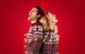 Side view of screaming young couple tied with Christmas garland over red background Royalty Free Stock Photo