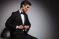 Side view of seated man in tuxedo buttoning his coat Royalty Free Stock Photo