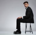 Side view of seated stylish young man in black tuxedo Royalty Free Stock Photo