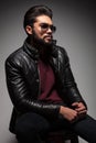 Side view of a seated young man in leather jacket and sunglasses Royalty Free Stock Photo