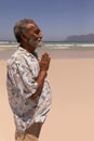 Senior black man with hands clasped praying on beach Royalty Free Stock Photo