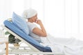 Side view of senior breast cancer patient wearing headscarf laying in bed and praying in the hospital room, cancer concept Royalty Free Stock Photo