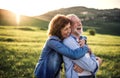 Side view of senior couple hugging outside in spring nature at sunset. Royalty Free Stock Photo