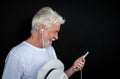 Side view of a senior man with beard and white hat looking at mobile phone smiling. Portrait of elderly retired enjoying Royalty Free Stock Photo