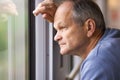 Side view of senior man in blue sweatshirt looks out of the window, traveling by train. Old man enjoying a train trip. Royalty Free Stock Photo