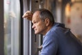 Side view of senior man in blue sweatshirt looks out of the window, traveling by train. Old man enjoying a train trip. Royalty Free Stock Photo