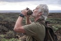 Side view of senior man with white beard enjoying the hike in arid landscape standing and drinking at water bottle. Horizon over Royalty Free Stock Photo