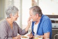 Side view of senior woman feeding husband while sitting at table Royalty Free Stock Photo