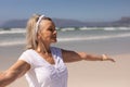 Side view of senior woman standing with arms outstretched at beach Royalty Free Stock Photo