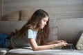 Focused young lady doing online homework on laptop