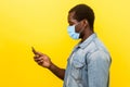 Side view of serious attentive man with surgical medical mask holding cellphone, typing or dialing number or reading news and