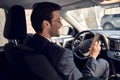 Side view of serious business man in suit using phone while sitting at the wheel in car Royalty Free Stock Photo