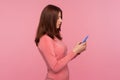 Side view serious concentrated brunette woman holding cell phone in hands, chatting or checking e-mail, gadget addiction Royalty Free Stock Photo