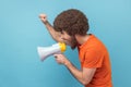 Side view of serious man raised hands and holding megaphone, screaming in loud speaker, protesting. Royalty Free Stock Photo