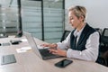 Side view of serious middle-aged business woman using typing on laptop computer sitting at workplace desk. Focused Royalty Free Stock Photo