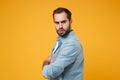 Side view of serious young bearded man in casual blue shirt posing isolated on yellow orange background in studio Royalty Free Stock Photo