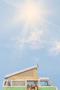 Seventies motor home in front of a blue sky with shining sun and copy space