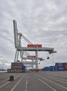 Side on view of several large Grey Container Cranes with their associated Stacked Containers ready for loading at Den Haag.