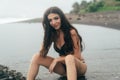 Side view of girl in bikini spends time on black sand beach. Young woman with long hair posing outdoor Royalty Free Stock Photo