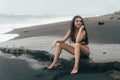 Side view of girl in bikini spends time on black sand beach. Young woman with long hair posing outdoor Royalty Free Stock Photo