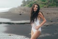 Side view of girl in bikini spends time on black sand beach. Young woman with long hair posing outdoor Royalty Free Stock Photo